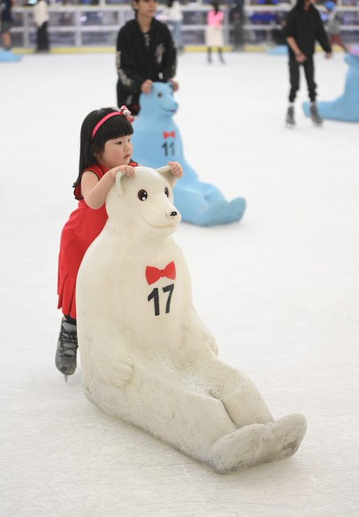 A young girl learns to skate with the assistance of a polar bear skating aid at SM Skating Megamall.