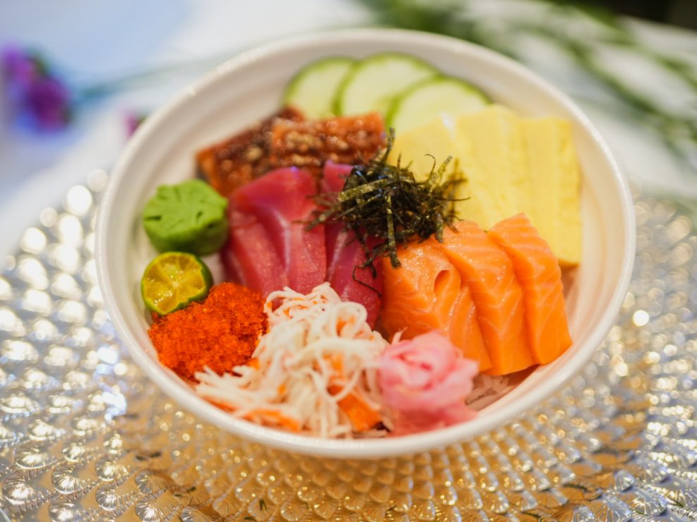 Experience the joy of chirashi with Sushi Nori: salmon, tuna, tamago, kani, and ebiko with cucumber and nori strips.